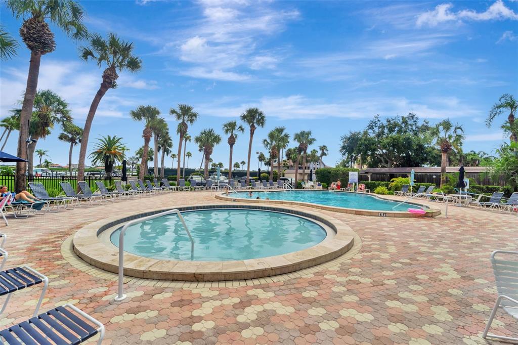 A circular hot tub sits on a paved pool deck next to a larger swimming pool — 5855 MIDNIGHT PASS ROAD UNIT 314, SARASOTA, FL
