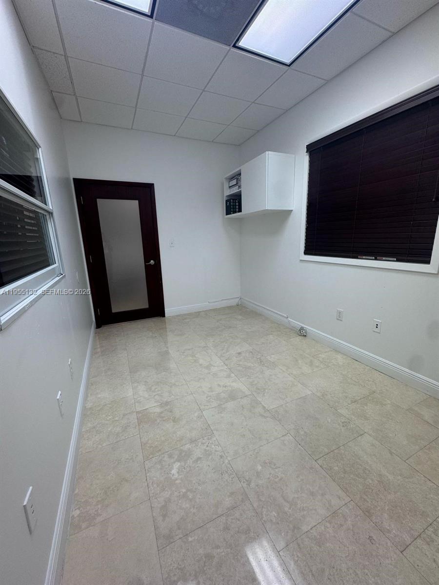 An empty office features white walls, tile flooring, a dark door, and a window — 7791 NW 46th St # 219, Doral FL 33166, DORAL, FL