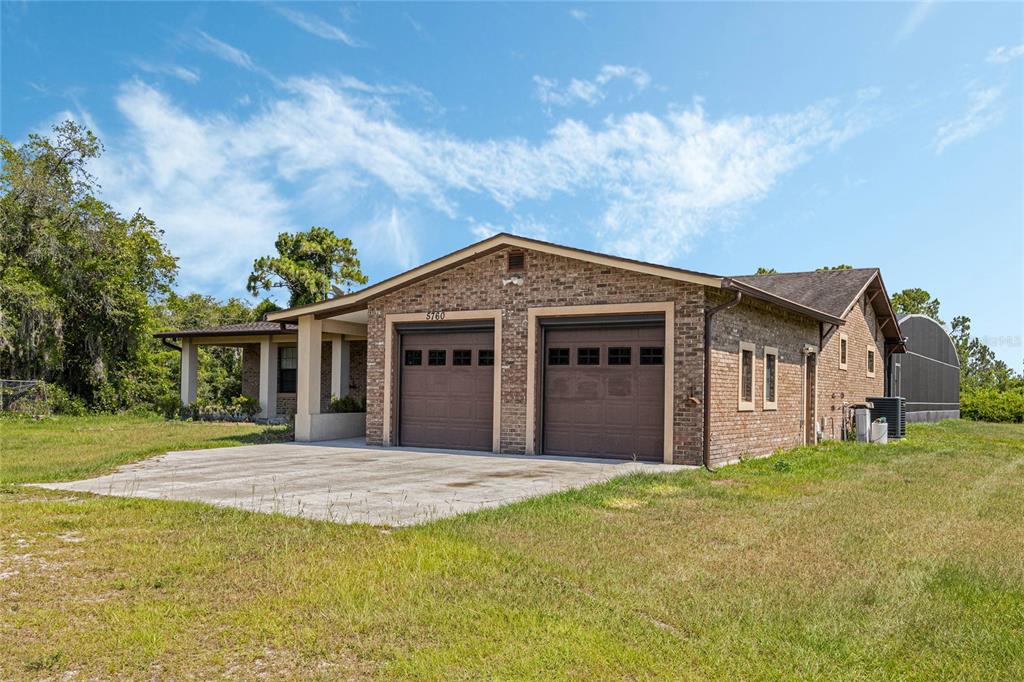 A brick house features a two-car garage, a covered porch, and a concrete driveway — 5760 LEON TYSON ROAD, ST CLOUD, FL