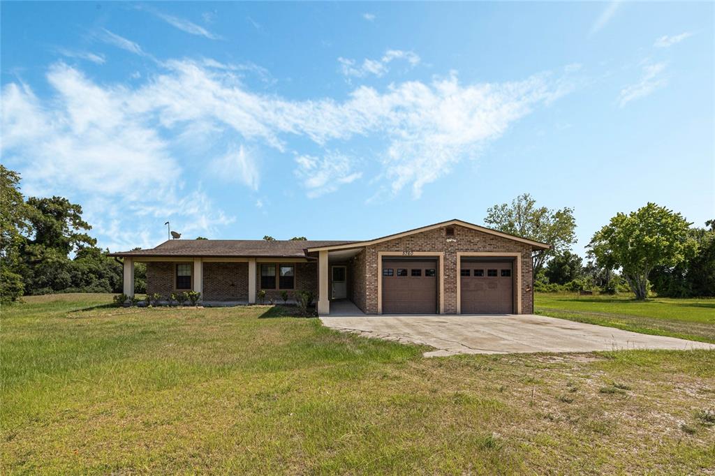 A single-story brick house with a two-car garage and a covered front porch — 5760 LEON TYSON ROAD, ST CLOUD, FL