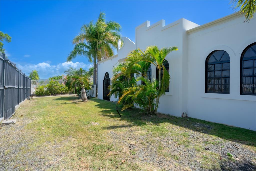A white house exterior with arched windows and palm trees on a grassy lot — 225 SANTA ISIDRA L CALLE B, FAJARDO, PR