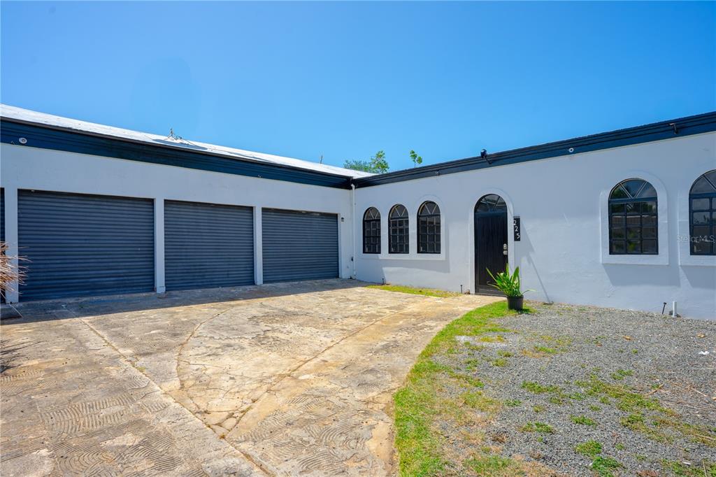 A white exterior building features three garage doors, arched windows, and a paved driveway — 225 SANTA ISIDRA L CALLE B, FAJARDO, PR