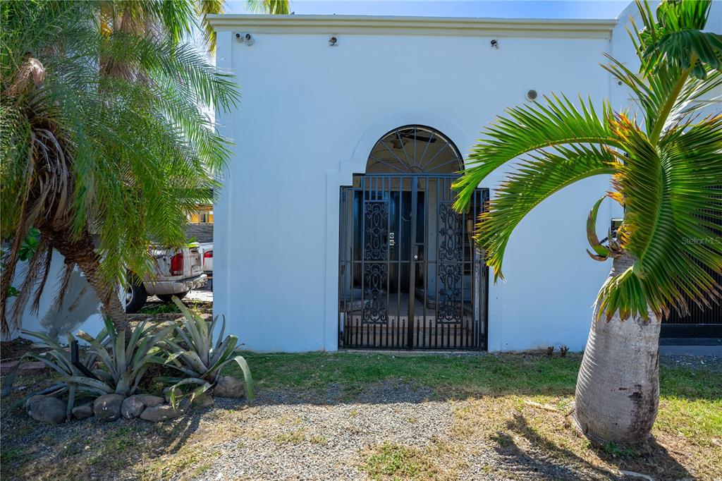 A white building exterior features an arched entryway with a black metal security gate — 225 SANTA ISIDRA L CALLE B, FAJARDO, PR
