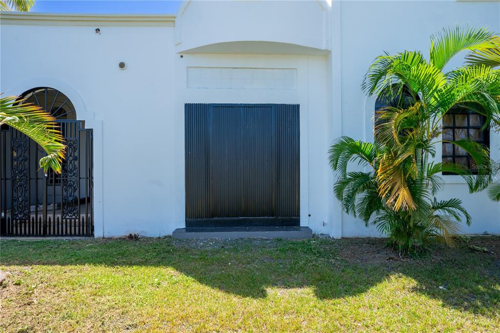 A white exterior wall features a black metal door and an arched gate — 225 SANTA ISIDRA L CALLE B, FAJARDO, PR