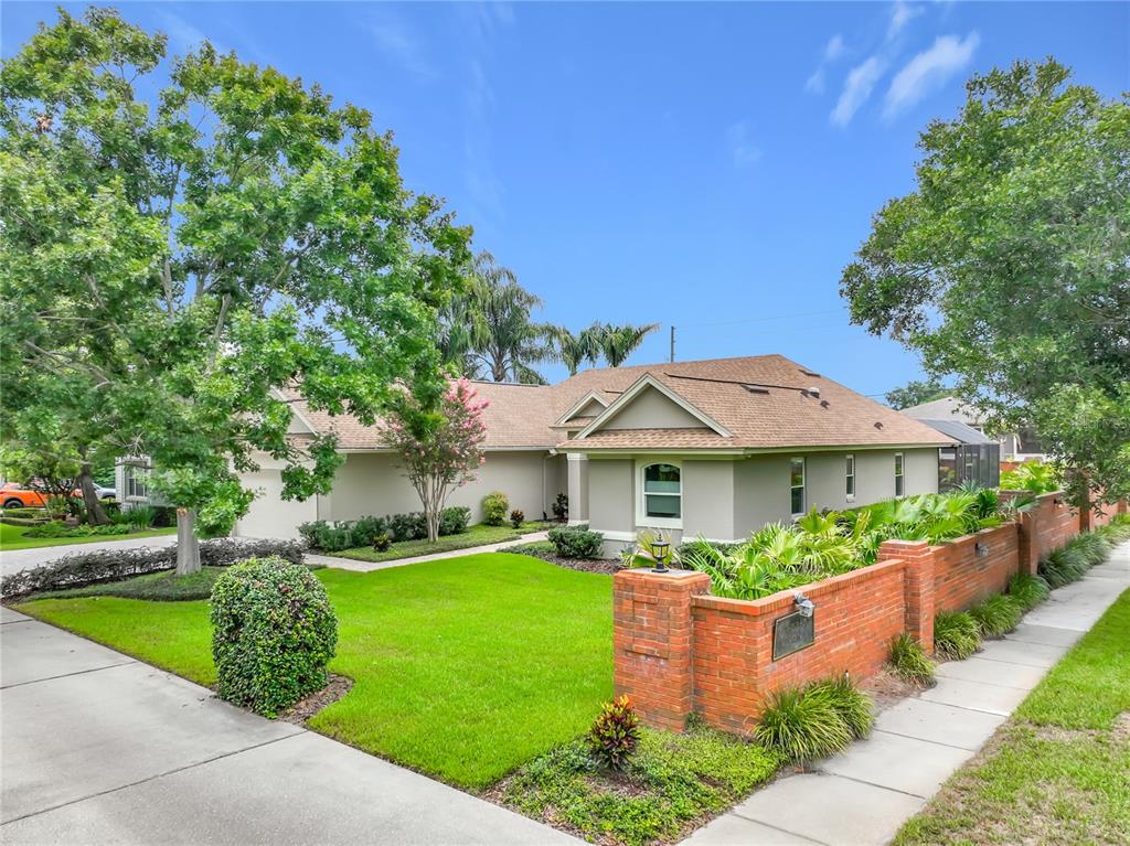 A single-story house with a tan exterior, brown roof, and a brick wall along the sidewalk — 2667 COCHISE TRAIL, WINTER PARK, FL