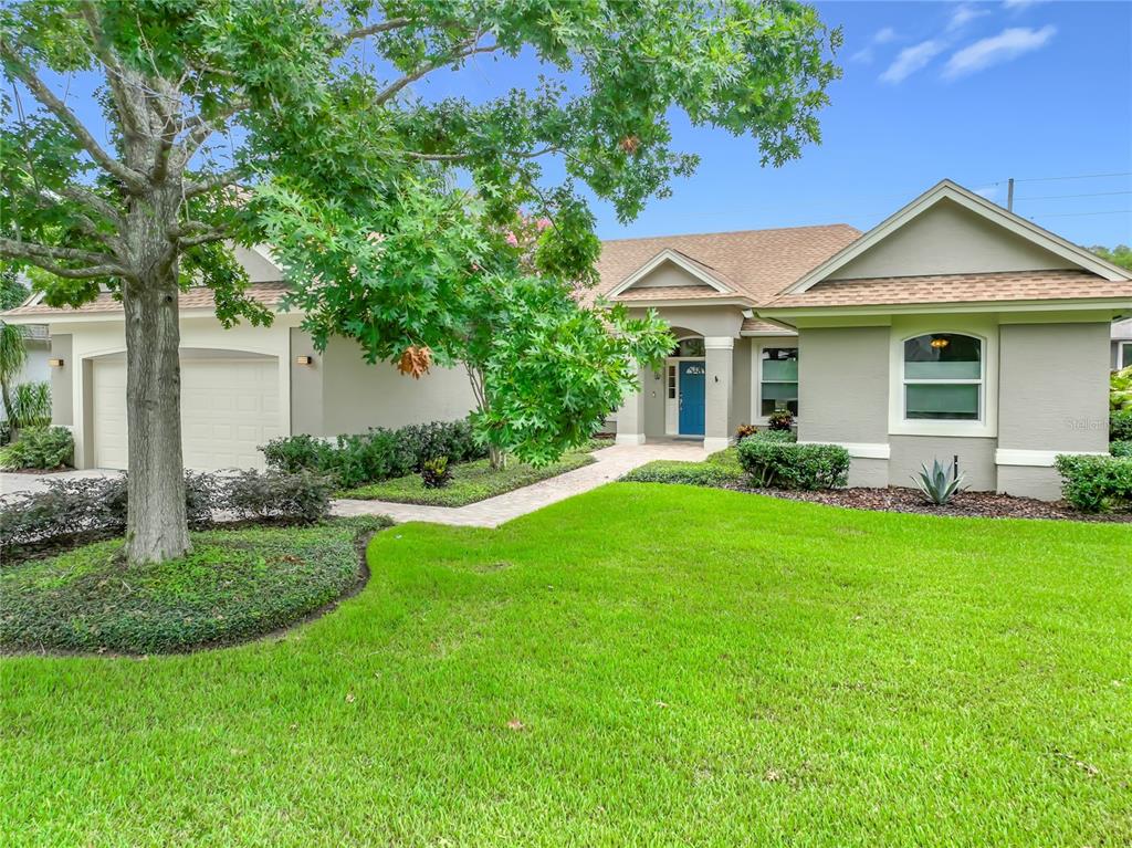 A single-story house with a beige exterior, a blue front door, and a manicured lawn — 2667 COCHISE TRAIL, WINTER PARK, FL