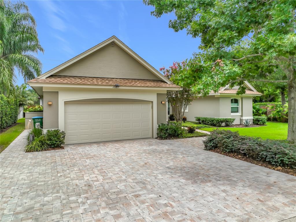 A beige house with a two-car garage and a paved driveway under a blue sky — 2667 COCHISE TRAIL, WINTER PARK, FL