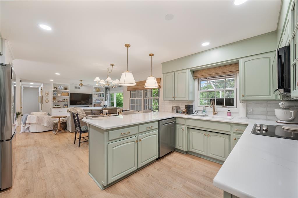 A kitchen with sage green cabinets, white countertops, and an island opens to a living room — 2718 BERKELEY AVENUE, LAKELAND, FL