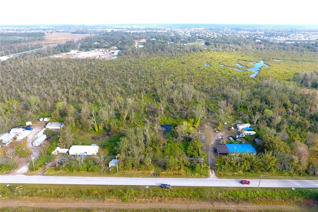 An aerial view shows two properties with small buildings and trailers along a rural road — 0 BILL TUCKER ROAD, WIMAUMA, FL