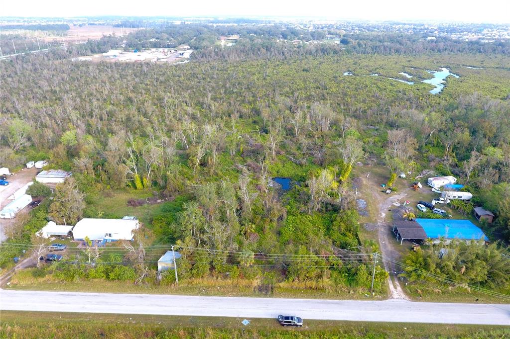 An aerial view shows a rural property with two houses, outbuildings, and dense wooded vegetation — 0 BILL TUCKER ROAD, WIMAUMA, FL