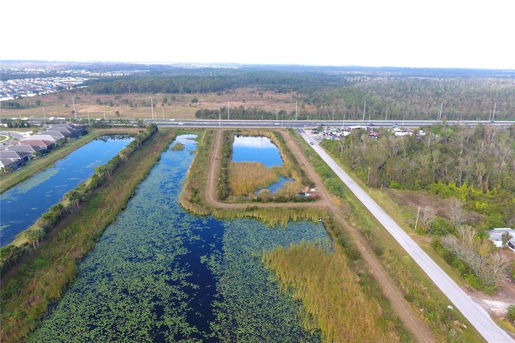 An aerial view shows a large retention pond beside a road and residential neighborhood — 0 BILL TUCKER ROAD, WIMAUMA, FL