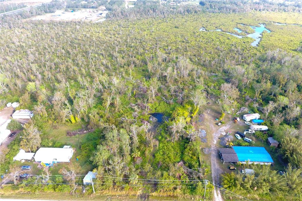 An aerial view shows two residential properties surrounded by dense woods and a small pond — 0 BILL TUCKER ROAD, WIMAUMA, FL