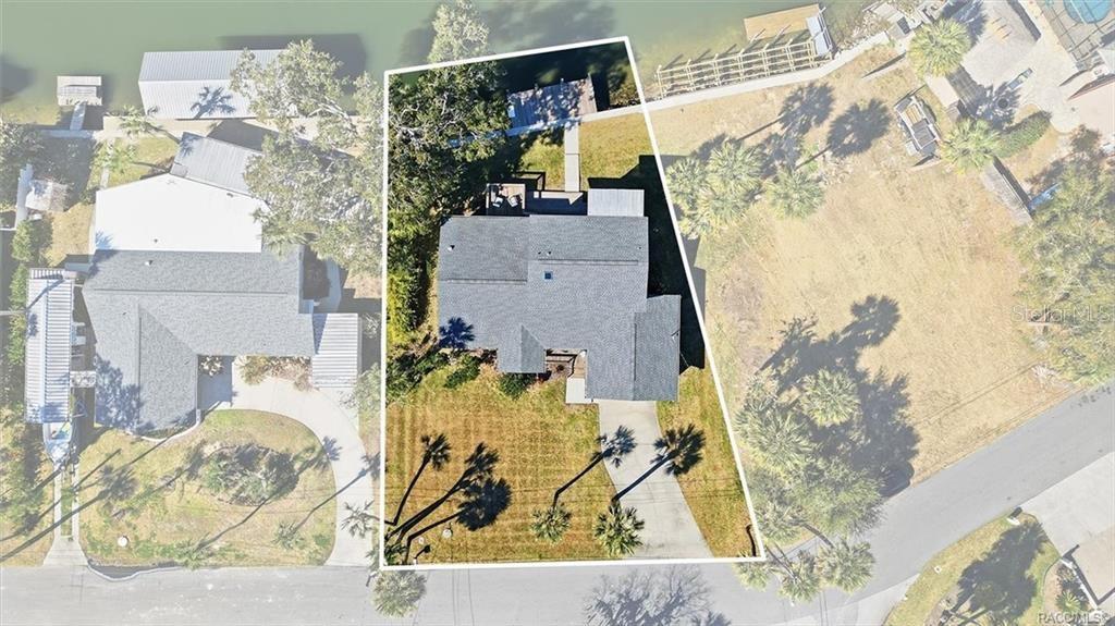 An aerial view shows a house with a gray roof situated on a waterfront lot — 9205 W HARBOR ISLE COURT, CRYSTAL RIVER, FL