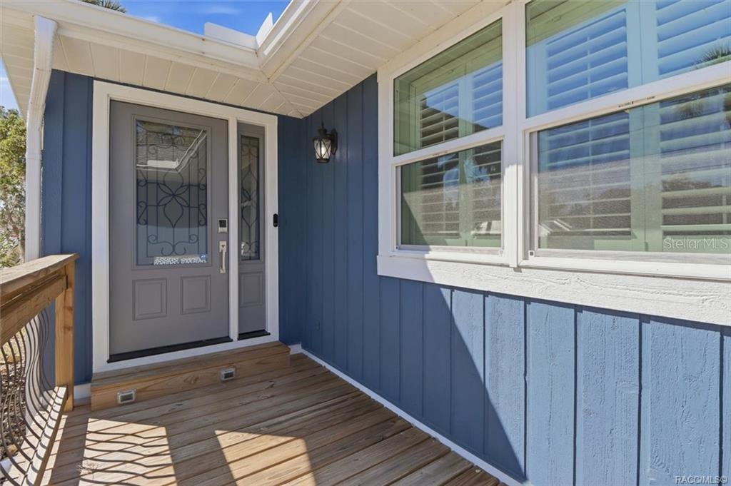 A blue-sided house exterior features a wooden porch, a gray front door, and white-trimmed windows — 9205 W HARBOR ISLE COURT, CRYSTAL RIVER, FL