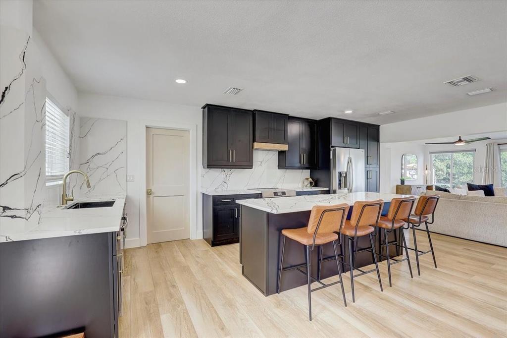 A modern kitchen features dark cabinets, white marble countertops, and a large central island — 265 96TH AVENUE N, ST PETERSBURG, FL