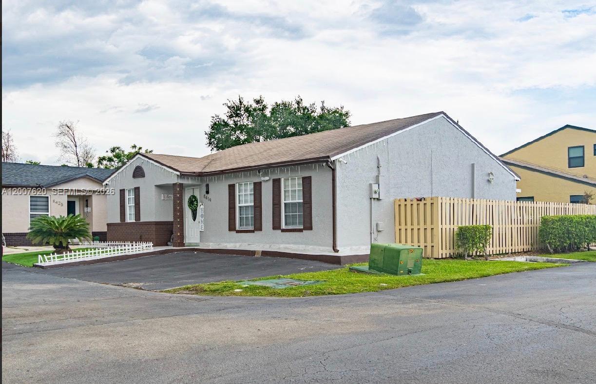 A single-story house with a gray stucco exterior, brown shutters, and a paved driveway — 8419 NW 193rd Ln, Hialeah FL 33015, HIALEAH, FL