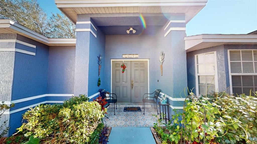 The exterior of a blue house features a double front door and a tiled porch — 3917 DERBY DRIVE, LAKELAND, FL