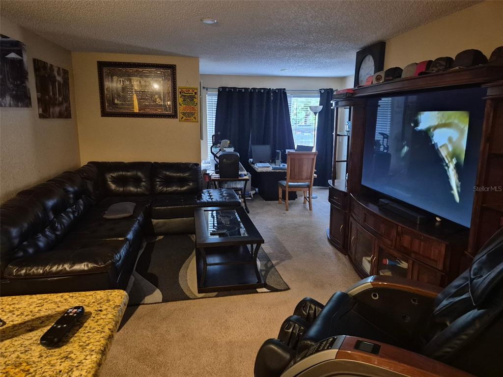 A living room features a large black leather sectional, a television console, and a desk — 5124 CONROY ROAD UNIT 11, ORLANDO, FL