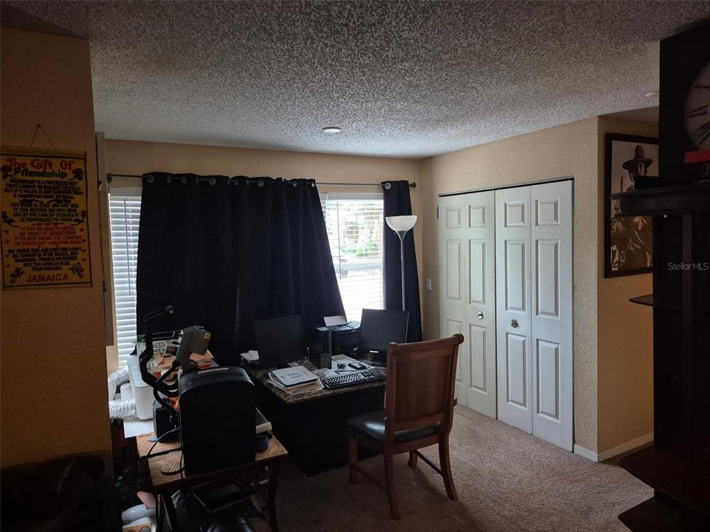 A home office features a desk with computer equipment, a wooden chair, and white closet doors — 5124 CONROY ROAD UNIT 11, ORLANDO, FL