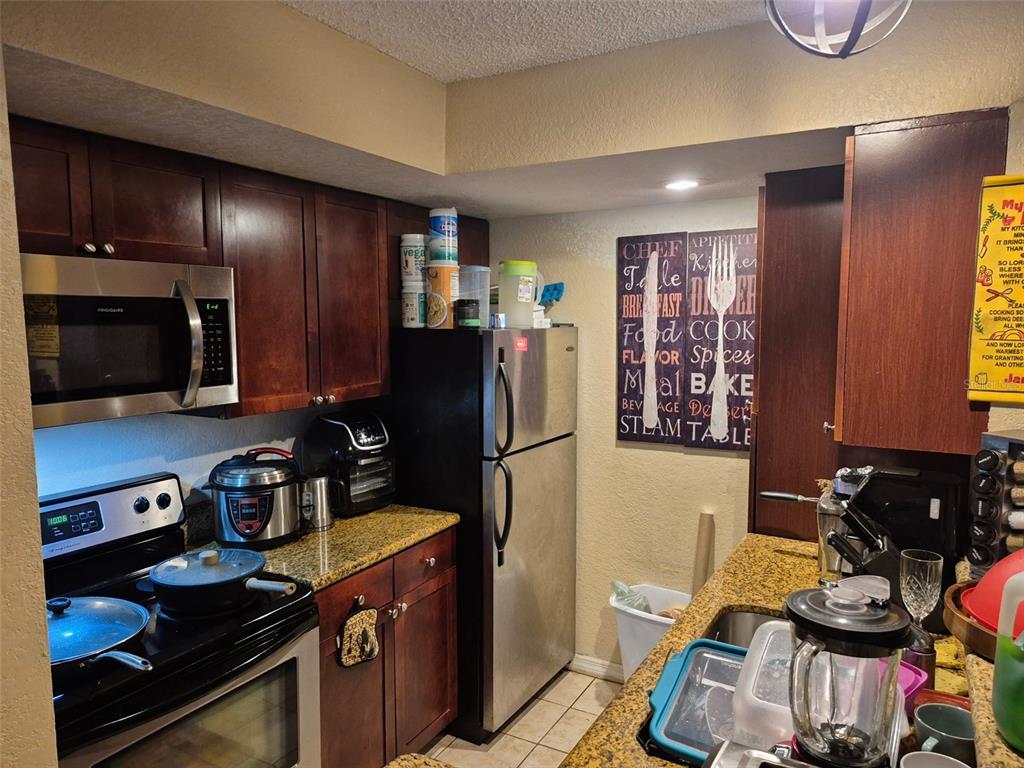 A kitchen with dark wood cabinets, stainless steel appliances, and granite countertops — 5124 CONROY ROAD UNIT 11, ORLANDO, FL