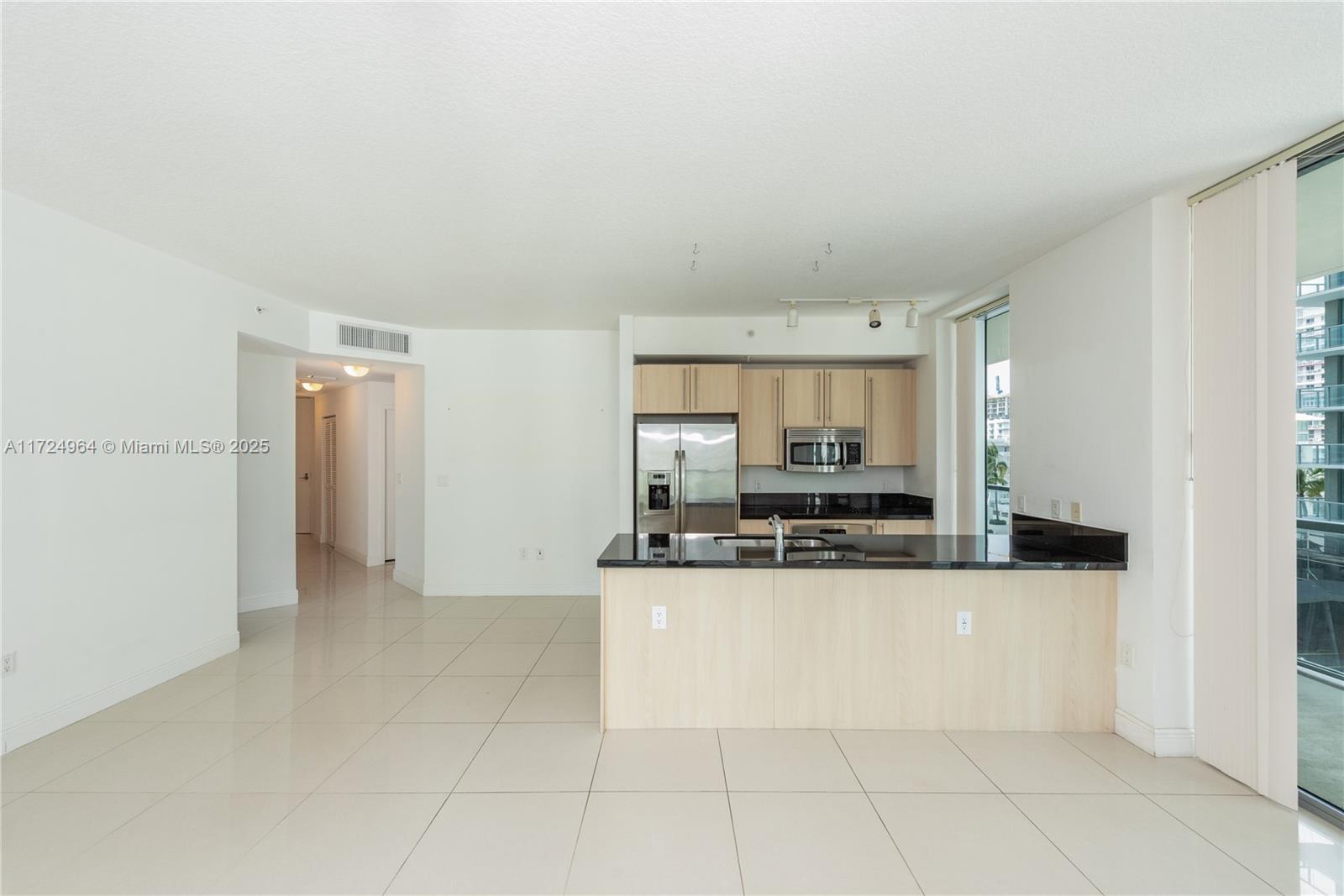 This kitchen features light wood cabinets, black countertops, and tile flooring in an open layout — 79 SW 12th St, Miami FL 33130, MIAMI, FL