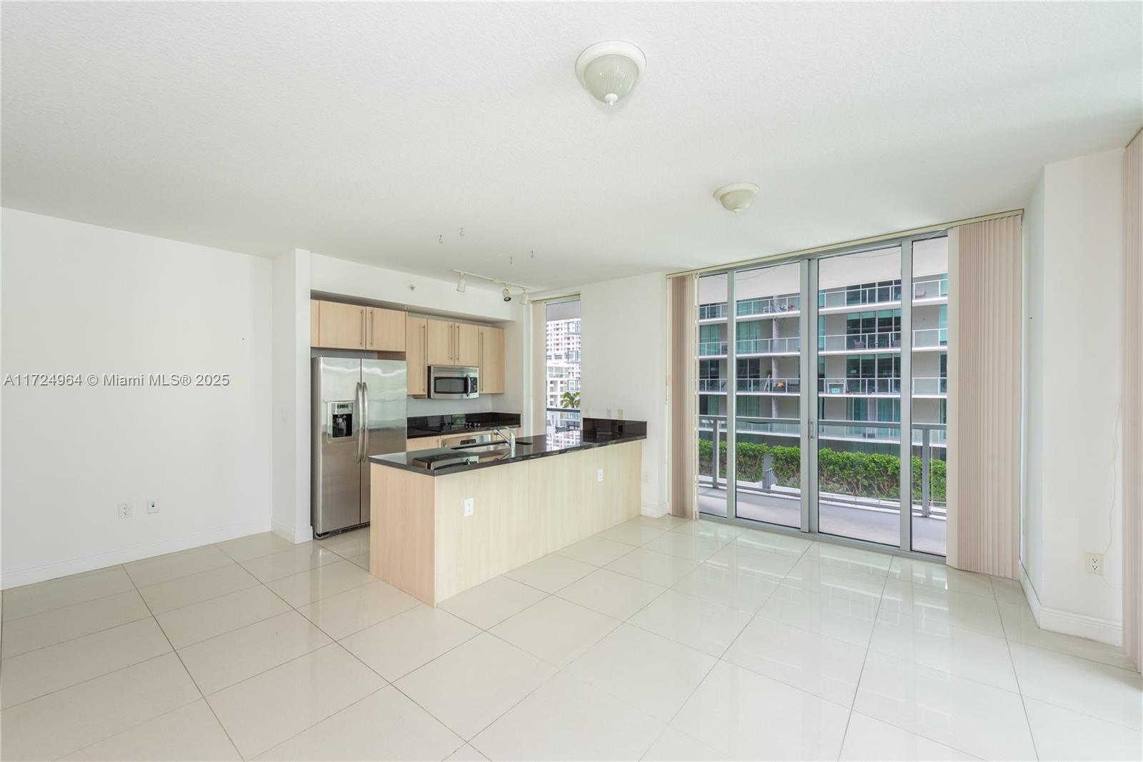 An open-concept kitchen with light wood cabinets and dark countertops overlooks a tiled living area — 79 SW 12th St, Miami FL 33130, MIAMI, FL