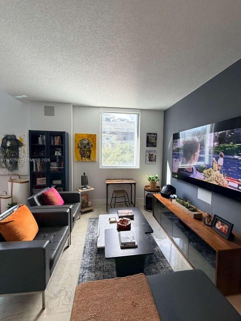 A modern living room features a dark accent wall, a large television, and leather seating — 1050 Brickell Ave # 222, Miami FL 33131, MIAMI, FL