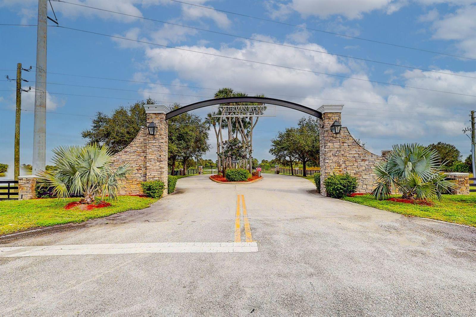 A stone-pillared entrance gate with a metal archway leads into Sherman Wood Ranches — 2831 SE 67th Place, Okeechobee FL 34974, OKEECHOBEE, FL