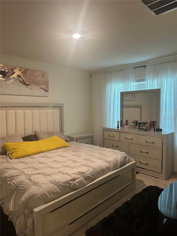 A bedroom features a tufted headboard, a matching dresser with a mirror, and a yellow pillow — 303 ALENCON WAY, KISSIMMEE, FL