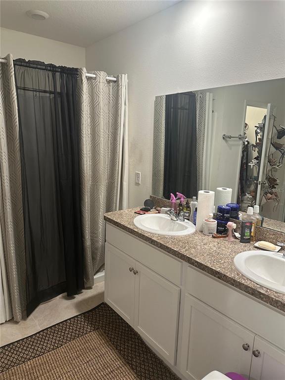 A bathroom features a double vanity with a speckled countertop, white cabinets, and a shower — 303 ALENCON WAY, KISSIMMEE, FL