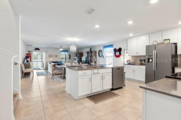 An open-concept kitchen with white cabinets and a center island overlooks a living area — 4382 FINCH LANE, KISSIMMEE, FL