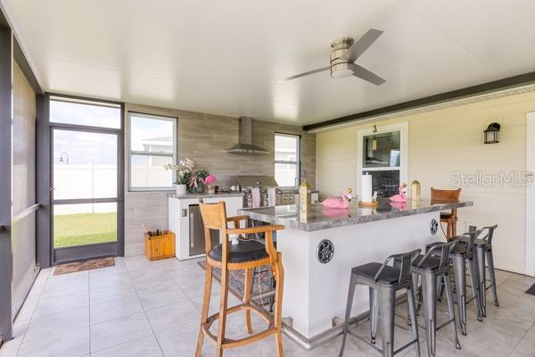 A covered outdoor patio features a kitchen island with bar seating and a grill area — 4382 FINCH LANE, KISSIMMEE, FL