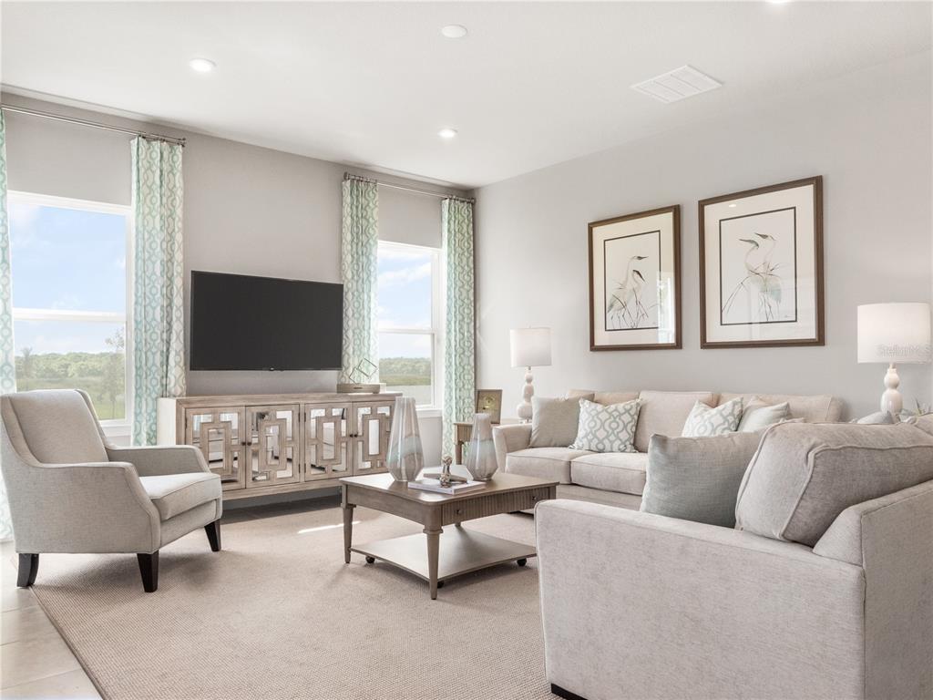 A living room features neutral furniture, a television on a console, and two framed prints — 6040 RIVERFRONT WAY, ST CLOUD, FL