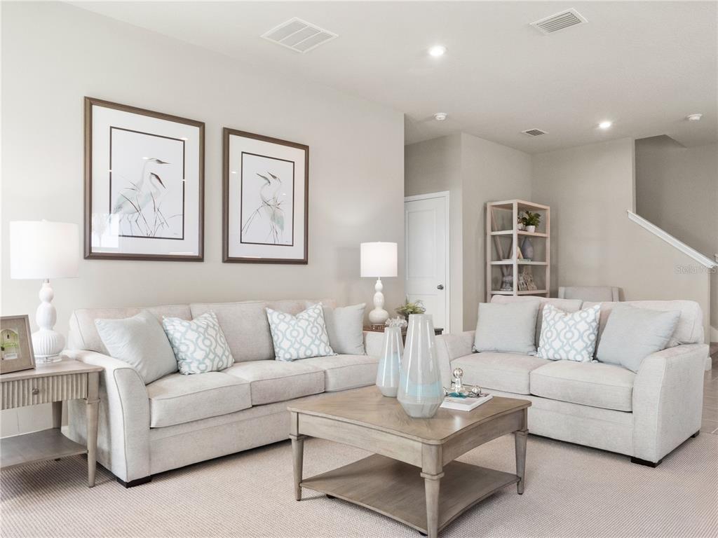 A living room features two light-colored sofas, a wooden coffee table, and framed wall art — 6040 RIVERFRONT WAY, ST CLOUD, FL