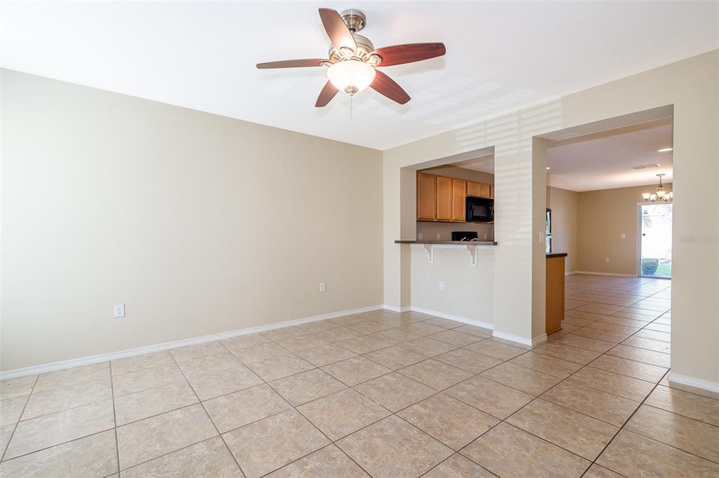 An empty dining area with beige walls, tile flooring, and a ceiling fan — 5087 DOMINICA DRIVE, KISSIMMEE, FL