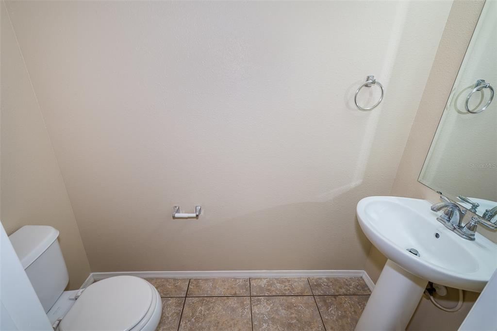 A small bathroom features a pedestal sink, a toilet, and a wall-mounted towel ring — 5087 DOMINICA DRIVE, KISSIMMEE, FL