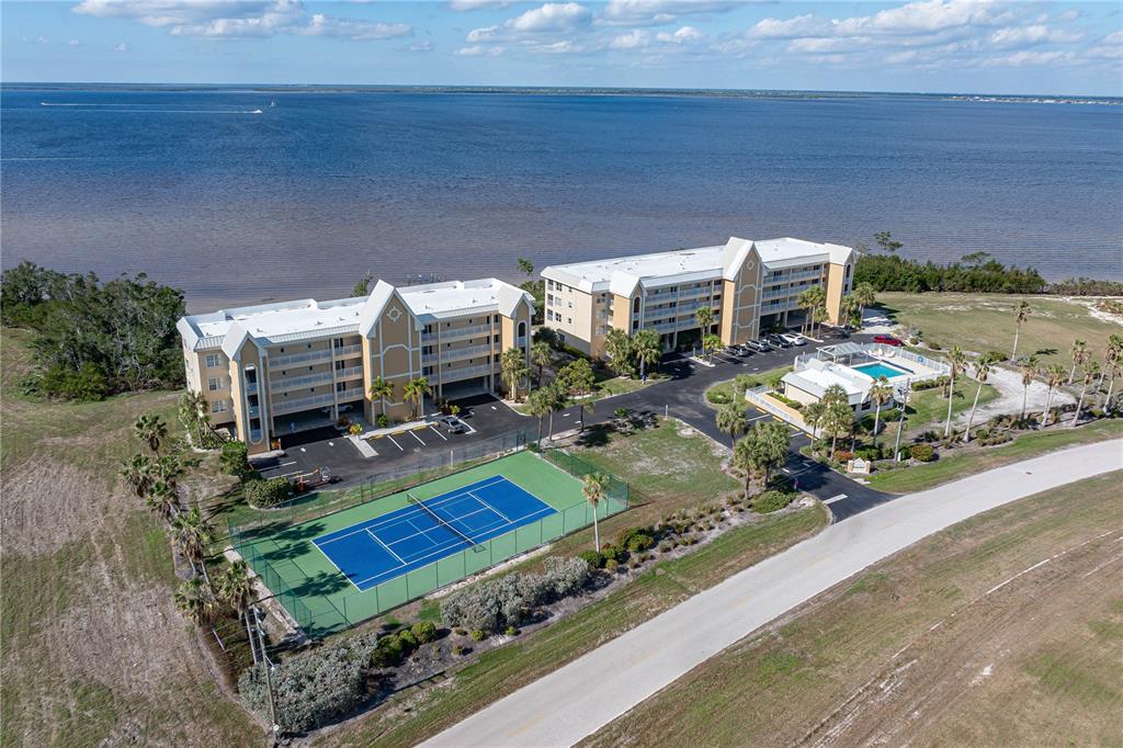 An aerial view shows two multi-story apartment buildings, a tennis court, and a swimming pool — 101 N MARION COURT UNIT 235, PUNTA GORDA, FL