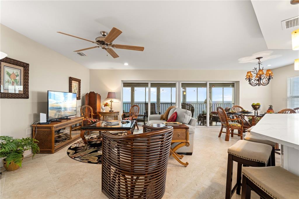 A living room with a ceiling fan, rattan furniture, and sliding glass doors overlooking the ocean — 101 N MARION COURT UNIT 235, PUNTA GORDA, FL