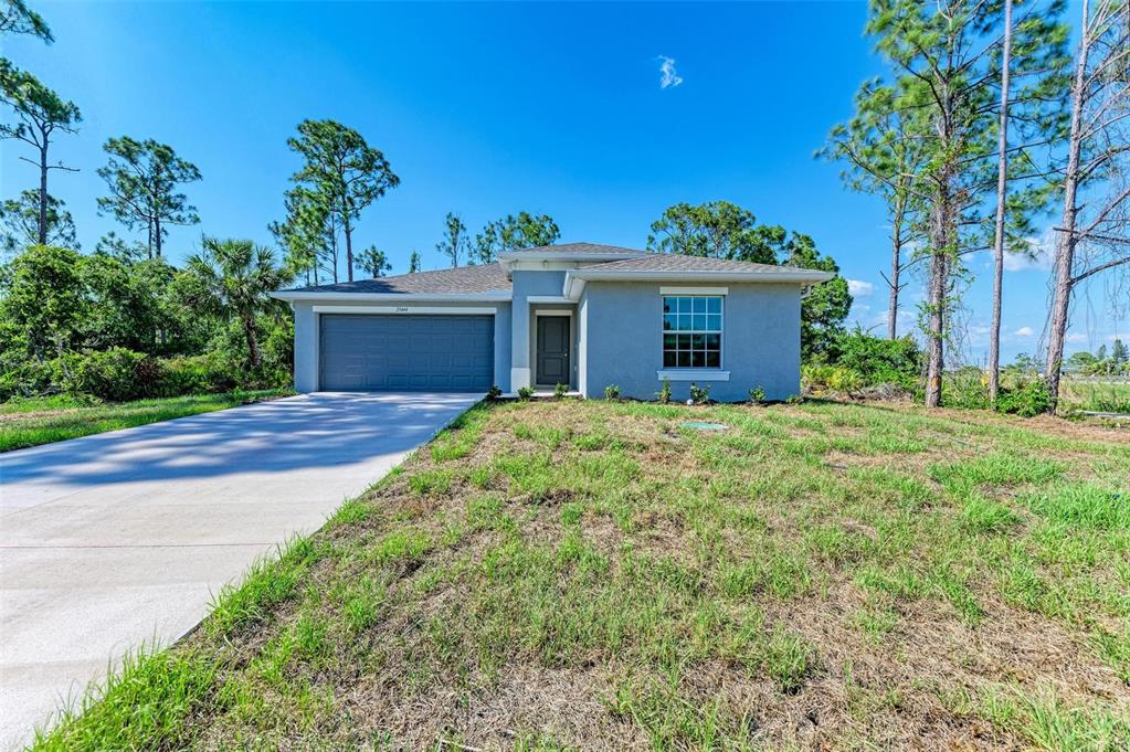 A single-story house with a gray exterior, a two-car garage, and a concrete driveway — 23444 STEEPLE AVENUE, PUNTA GORDA, FL
