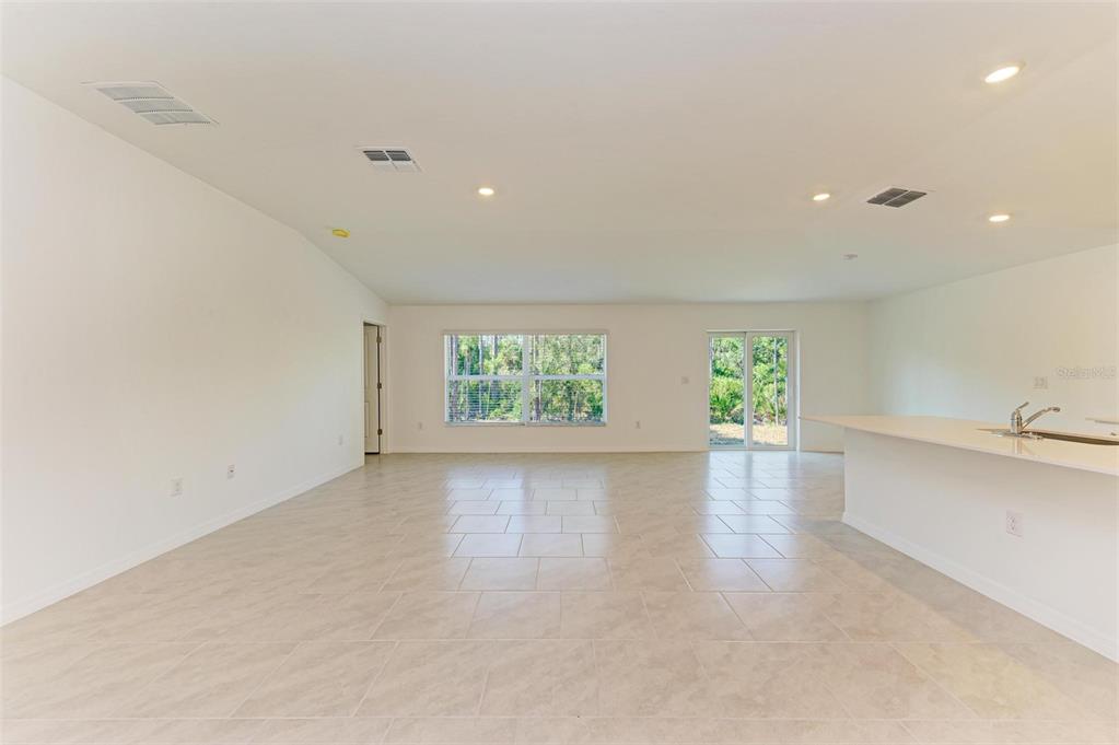 An open-concept living area features light tile flooring, white walls, and a kitchen island — 23444 STEEPLE AVENUE, PUNTA GORDA, FL
