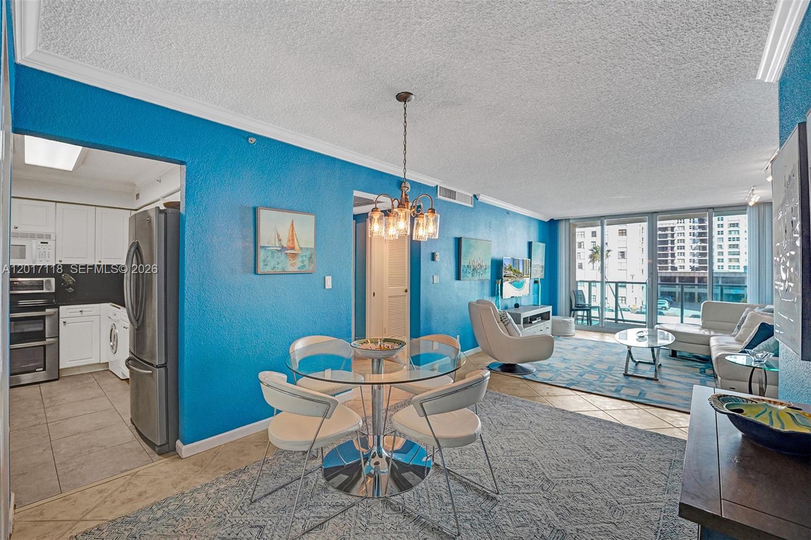 A dining area with a glass table and chairs opens into a living room with blue walls — 2501 S Ocean Dr, Hollywood FL 33019, HOLLYWOOD, FL
