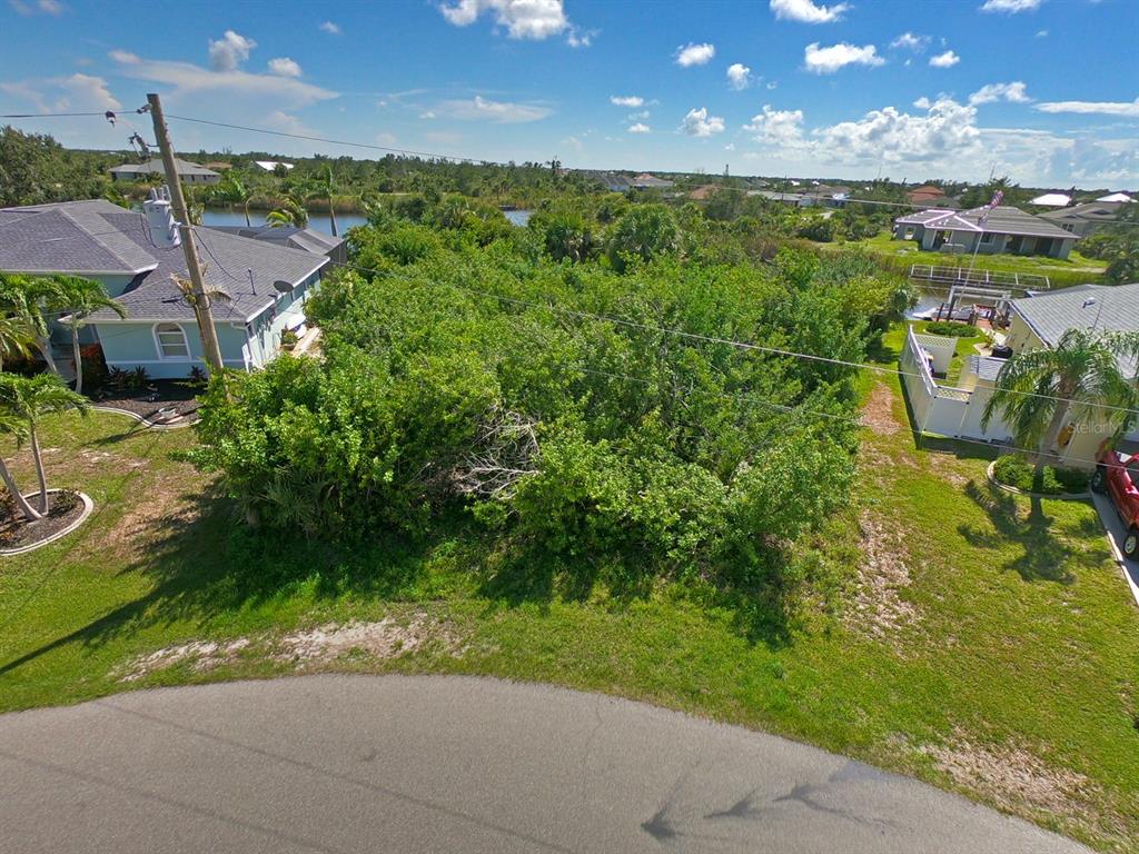 An elevated view of a vacant, tree-covered residential lot situated between two houses — 9604 ARNAZ CIRCLE, PORT CHARLOTTE, FL