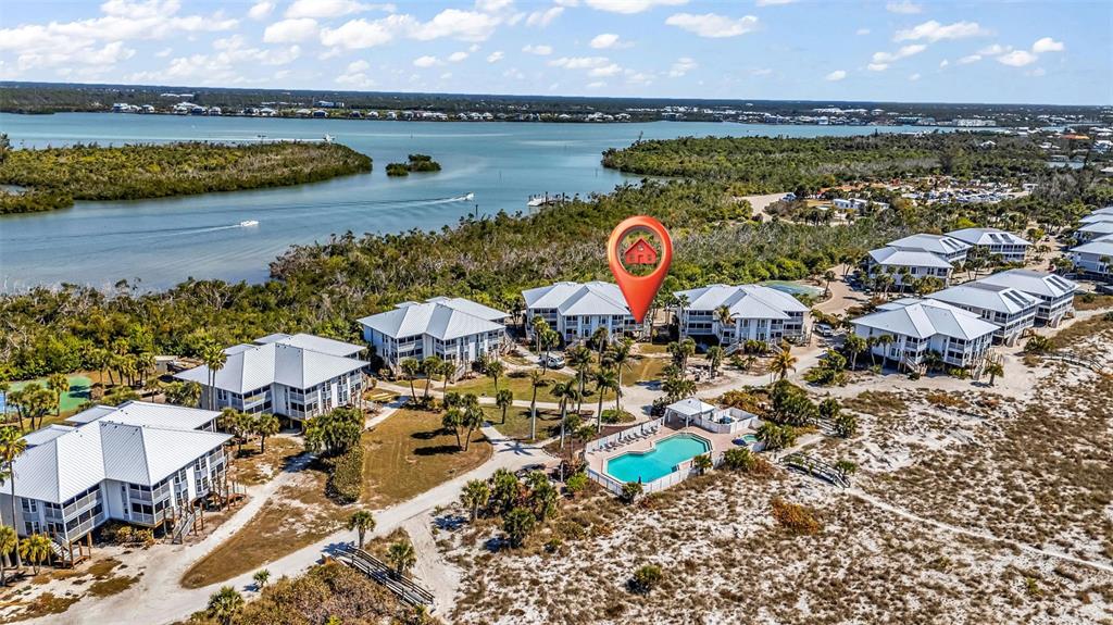 This aerial view shows a coastal residential complex with a swimming pool and water access — 7454 PALM ISLAND DRIVE UNIT 3311, PLACIDA, FL