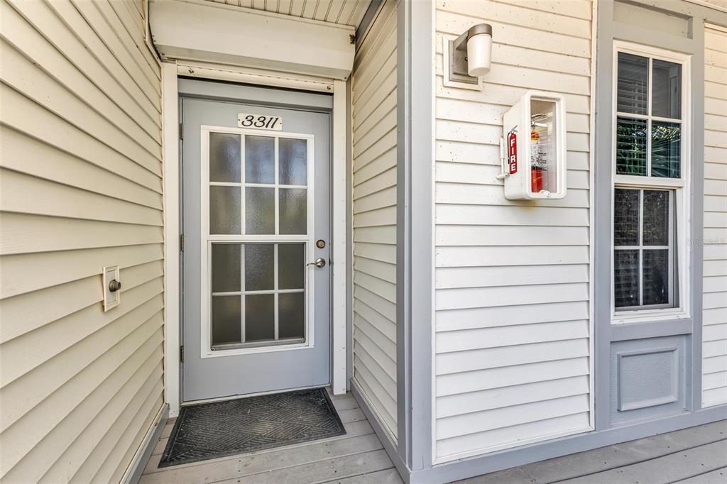 A light gray door with a glass window panel sits on a wooden porch — 7454 PALM ISLAND DRIVE UNIT 3311, PLACIDA, FL