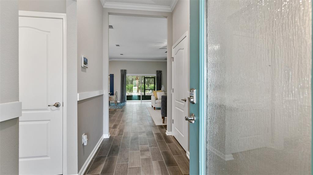 A view from a doorway looking down a hallway with tile floors toward a living area — 142 GREENWOOD DRIVE, PALM COAST, FL