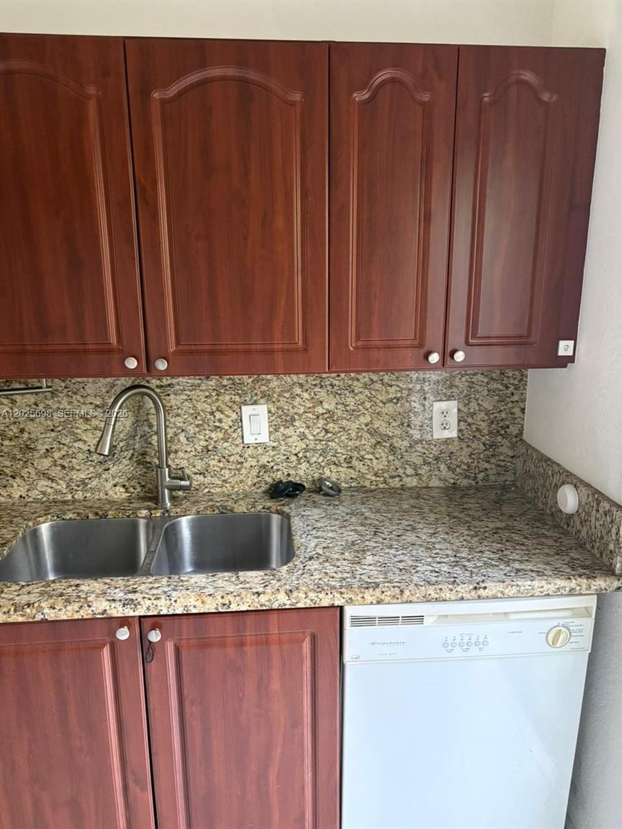 A kitchen features wood cabinets, granite countertops, a double sink, and a white dishwasher — 117 SE 3rd Ave # 7, Hallandale Beach FL 33009, HALLANDALE BEACH, FL