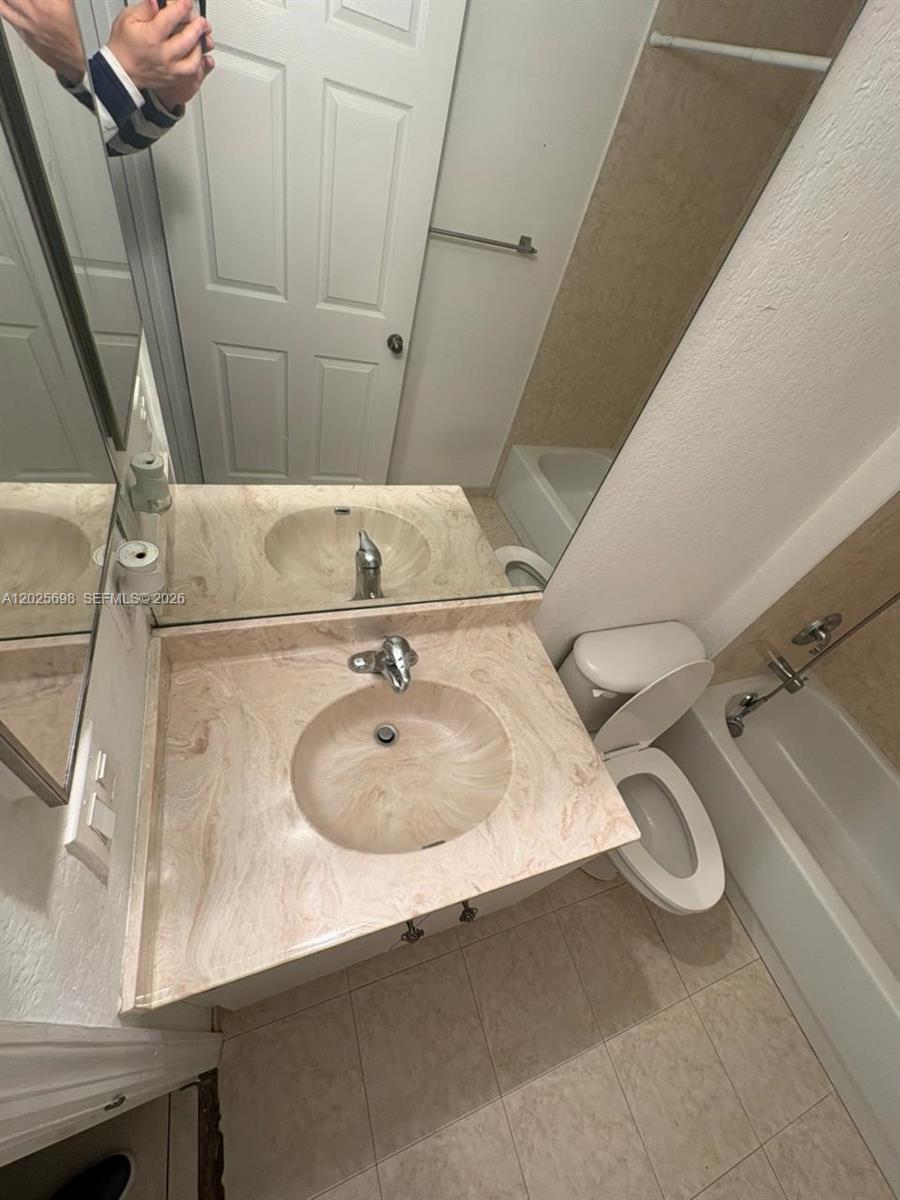 A bathroom features a beige vanity with a sink, a toilet, and a bathtub — 117 SE 3rd Ave # 7, Hallandale Beach FL 33009, HALLANDALE BEACH, FL