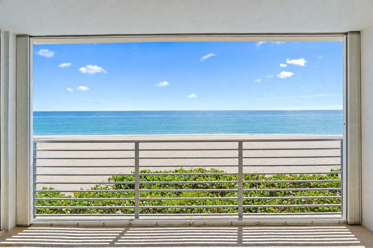 A balcony with a metal railing overlooks a sandy beach and the ocean — 900 Ocean Drive # 106, Juno Beach FL 33408, JUNO BEACH, FL