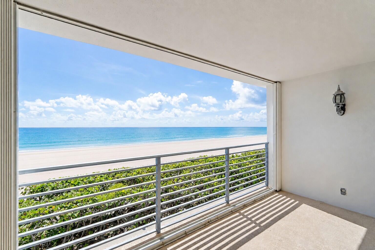 A balcony with a metal railing overlooks a sandy beach and the ocean — 900 Ocean Drive # 106, Juno Beach FL 33408, JUNO BEACH, FL
