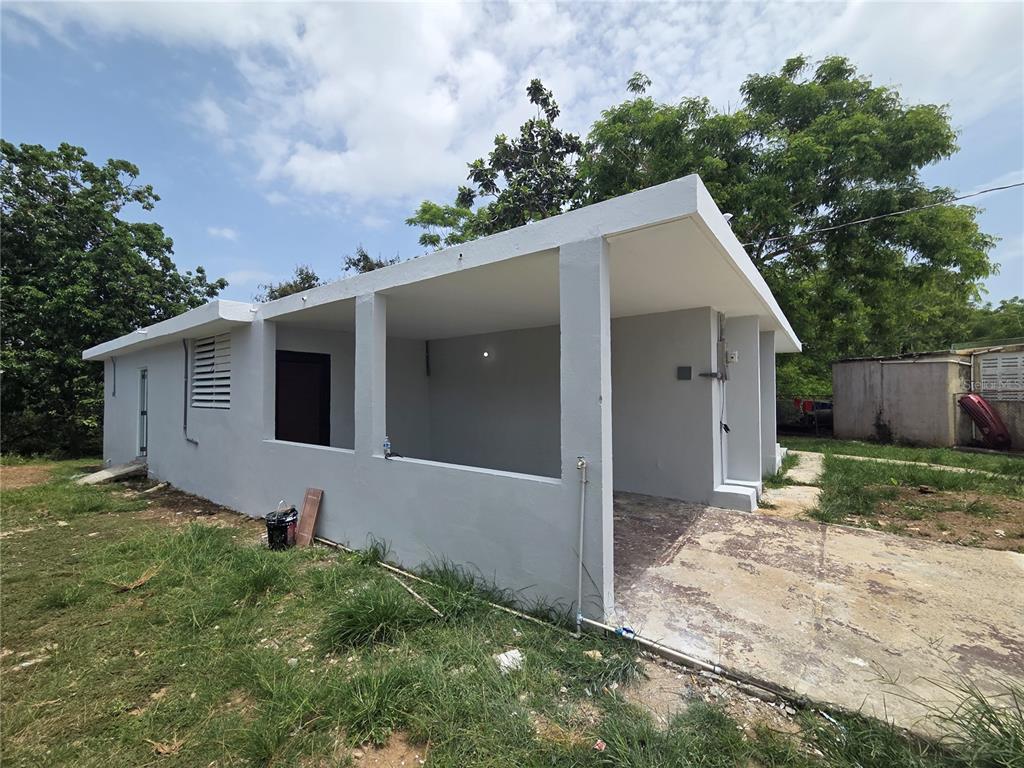 A gray, single-story house features an open-air carport and a concrete driveway — Colinas de Vista Alegre COLINAS DE VISTA ALEGRE, BAYAMON, PR